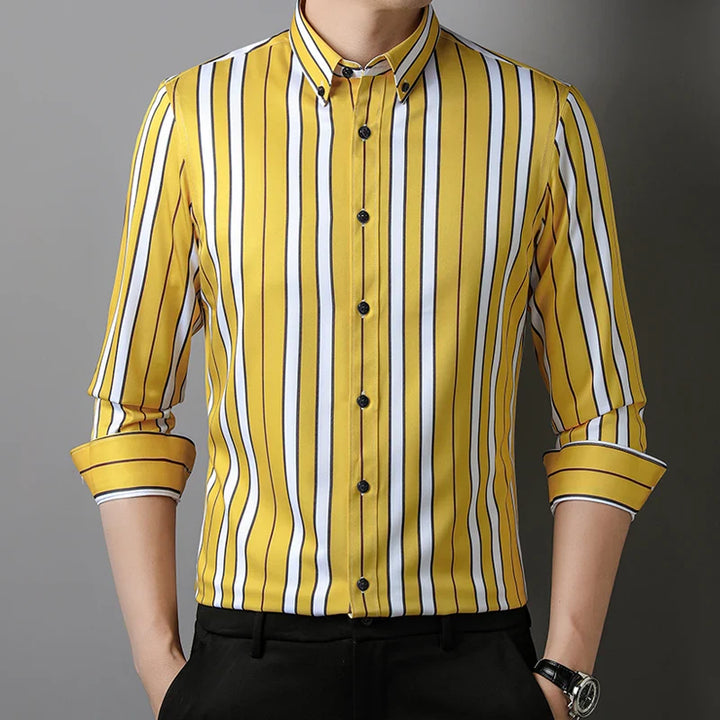 A man wearing the Hamilton Executive Classic Fit Shirt in spring colors—a yellow button-up with vertical black and white stripes, sleeves rolled up, and paired with black pants.