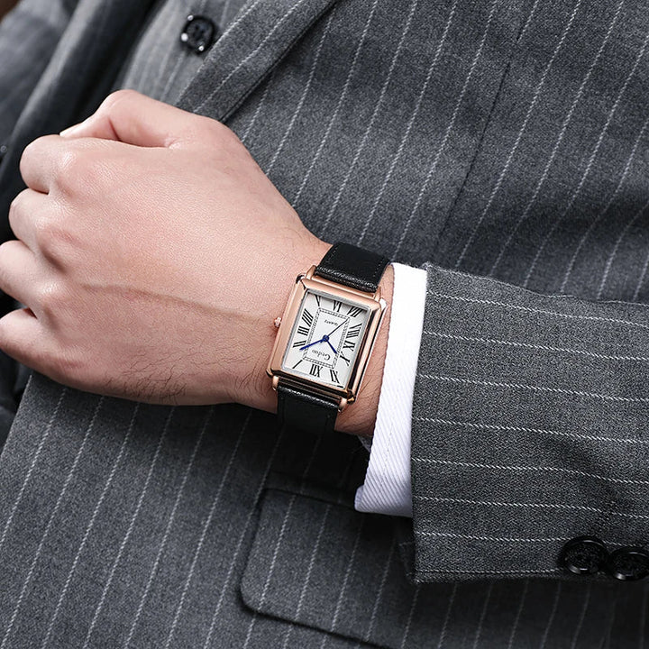A person in a gray pinstripe suit and white shirt displays a luxury watch with Roman numerals on the face and a premium leather band.