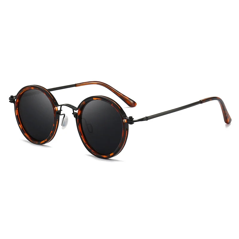 Round Ruby Ray Sunglasses with dark lenses, tortoiseshell-patterned frames, and black metal arms with matching tips. Featuring UV400 protection, they’re stylishly angled with one arm extended outward.