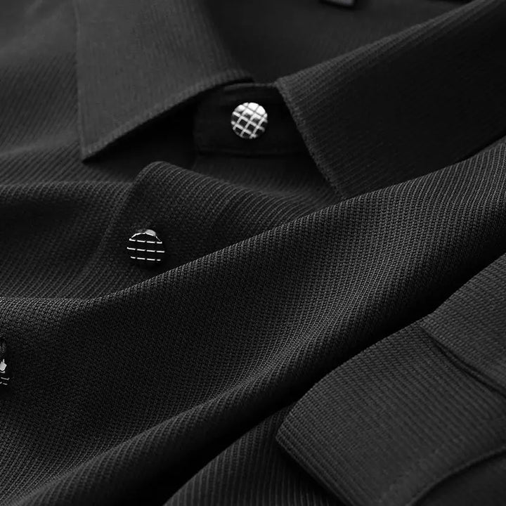 Close-up of a black wrinkle-resistant button-up dress shirt with distinctive round buttons featuring a silver grid pattern, highlighting the fabric weave and button details.