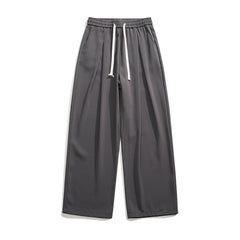 Wide-leg, charcoal gray GOAT Joggers with an elastic waistband and white drawstrings, displayed flat on a white background. These streetwear joggers feature side pockets, a relaxed fit, and effortlessly combine comfort with style.