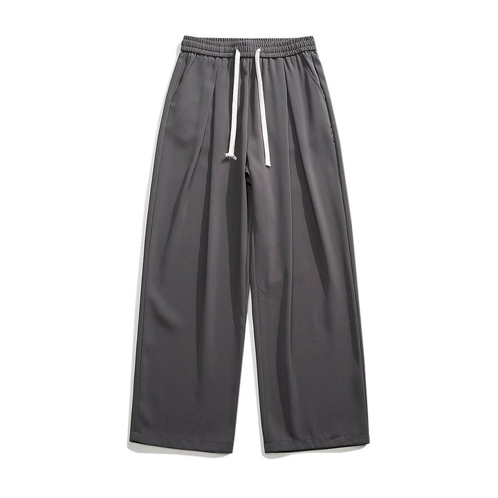Wide-leg, charcoal gray GOAT Joggers with an elastic waistband and white drawstrings, displayed flat on a white background. These streetwear joggers feature side pockets, a relaxed fit, and effortlessly combine comfort with style.