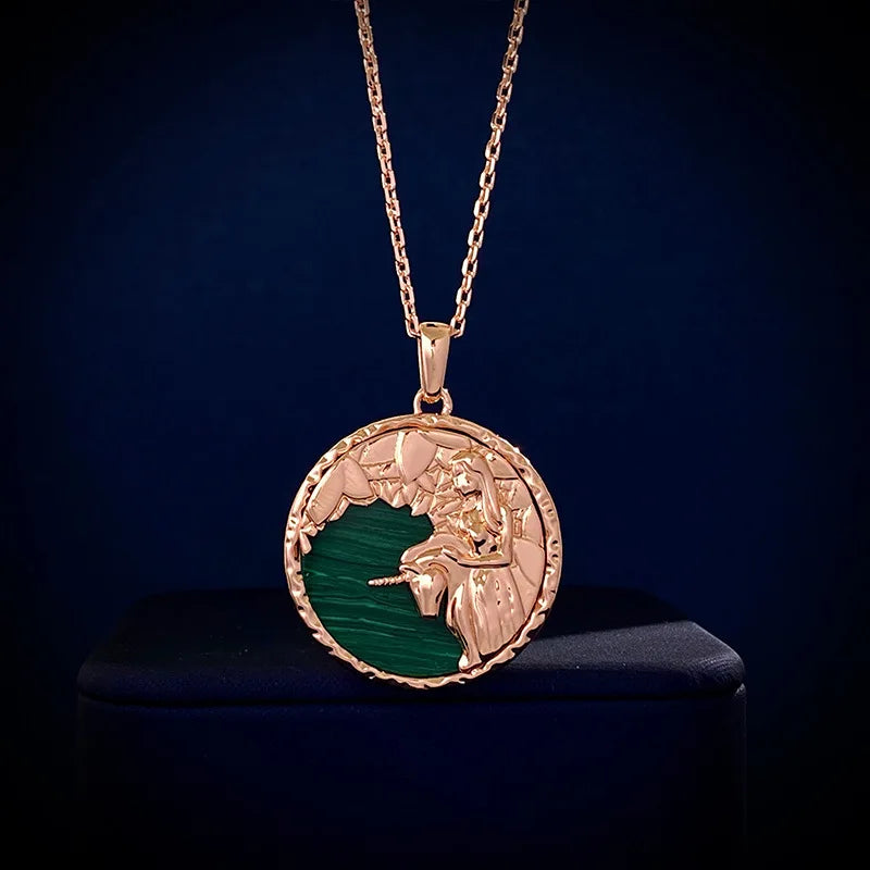 Gold chain necklace with a round pendant featuring a raised angel design over a green background, displayed against a dark backdrop—a unique piece of astrology jewelry.
