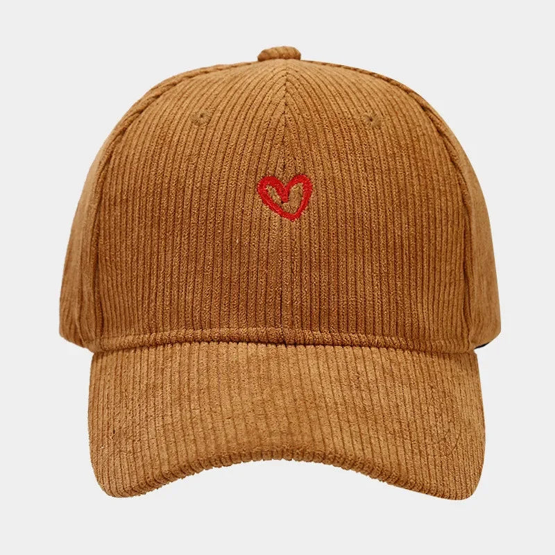 A brown corduroy baseball cap featuring heart embroidery on the front center and a comfortable FlexFit band, displayed against a plain white background.