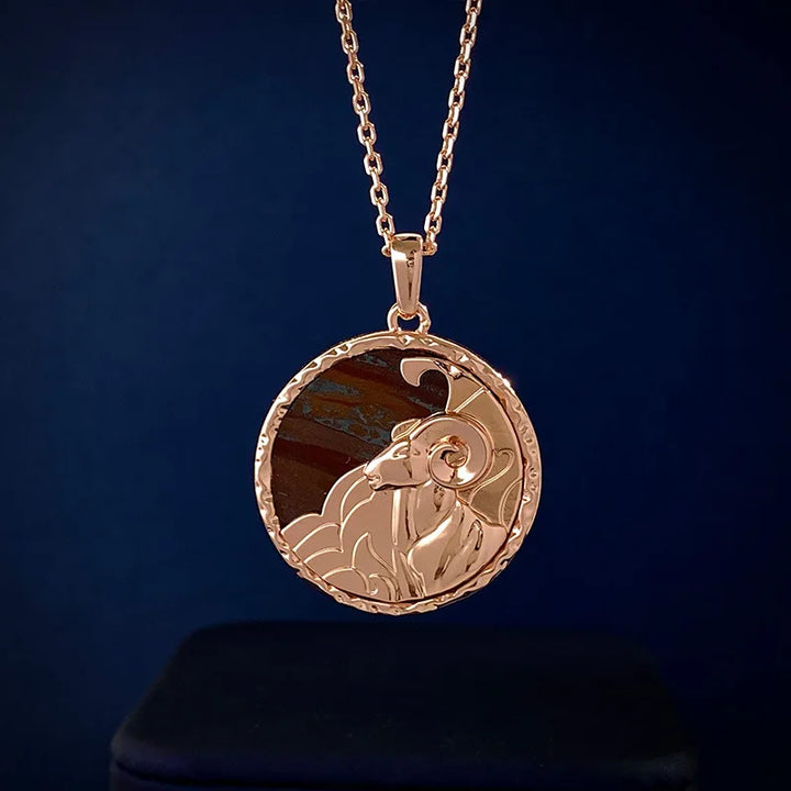 A gold zodiac necklace featuring a detailed engraving of a rams head with curled horns and a partial cloud design, this stunning piece of astrology jewelry stands out against a dark blue background.