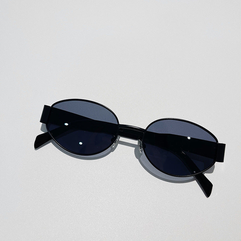 A pair of black vintage-inspired sunglasses with dark lenses and UV400 protection rests on a light gray surface, casting a slight shadow.