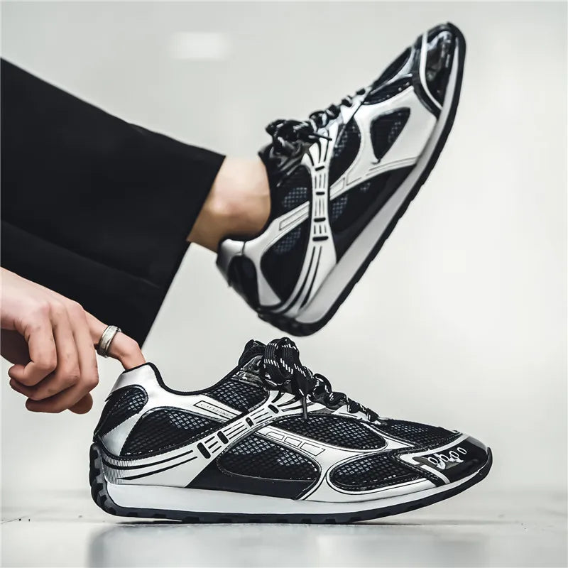 A person wearing black and white athletic sneakers with a modern, geometric design, featuring a non-slip outsole and cushioned insole. One foot is on the ground while the other is raised, adjusting the shoe. The background is plain and light-colored.