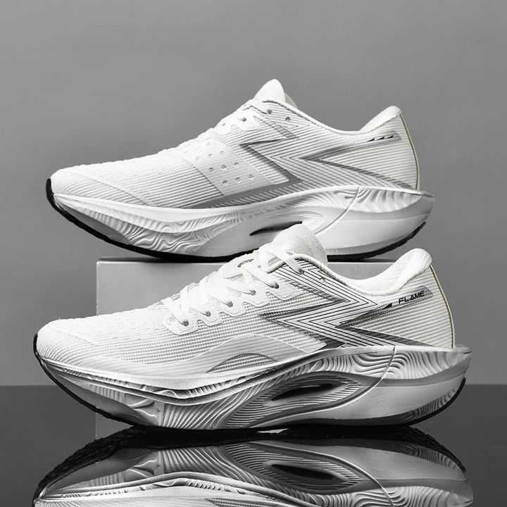 A pair of ultra-lightweight white athletic running shoes with textured soles and gray accents are displayed side-by-side against a gray background, one resting on a box and the other on a shiny black surface.