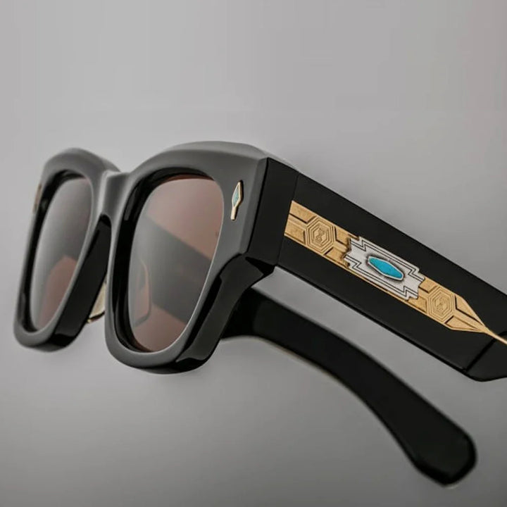 Black, vintage-inspired sunglasses with thick frames, featuring gold geometric designs and a turquoise accent on the arms, offer UV400 protection against harmful rays, shown against a neutral background.