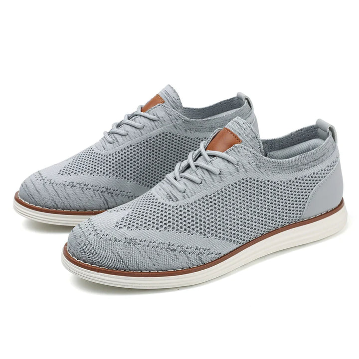 A pair of light gray breathable knit sneakers with white soles, subtle decorative stitching, and brown accents on the tongue, displayed on a white background.