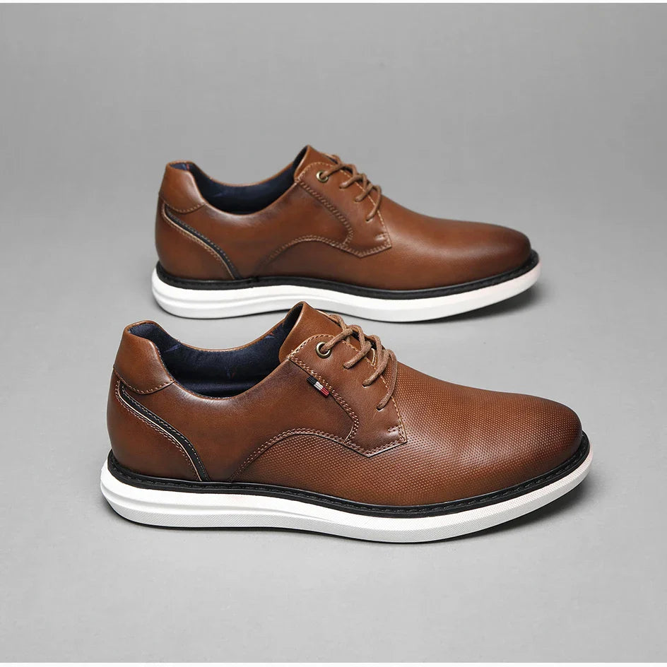 A pair of brown genuine leather oxford lace-up casual shoes with white soles, displayed side by side on a gray background. The shoes feature visible stitching, traditional detailing, and a subtle textured pattern on the surface.