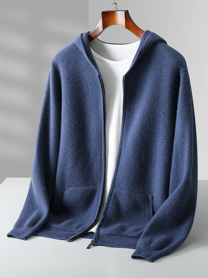 A blue zip-up hoodie with a hood and front pockets is displayed on a hanger over a plain white T-shirt, evoking the cozy feel of an autumn winter cardigan, set against a light gray background.