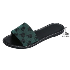 A black slide sandal with a green fabric strap featuring a black pattern, this slide silhouette from French Sole boasts white stitching along the sole edge and a comfortable 1.5 cm (0.59 inch) heel—timeless shoes for any wardrobe.