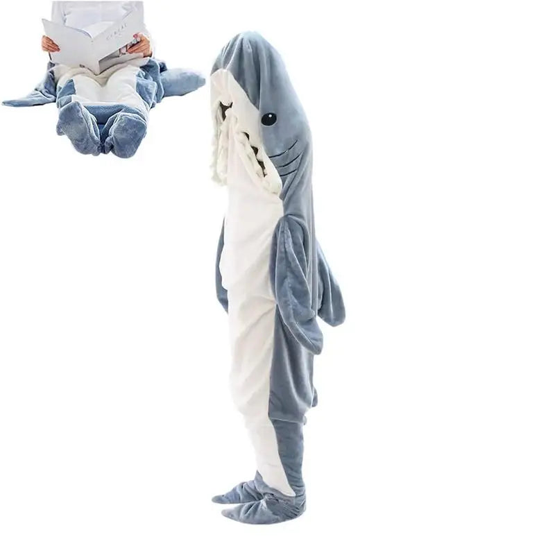 A person wearing soft, full-body shark pajamas that cover them from head to toe. Inset shows someone sitting with legs inside the cozy pajamas, appearing as if theyre in a shark’s mouth while reading a book.