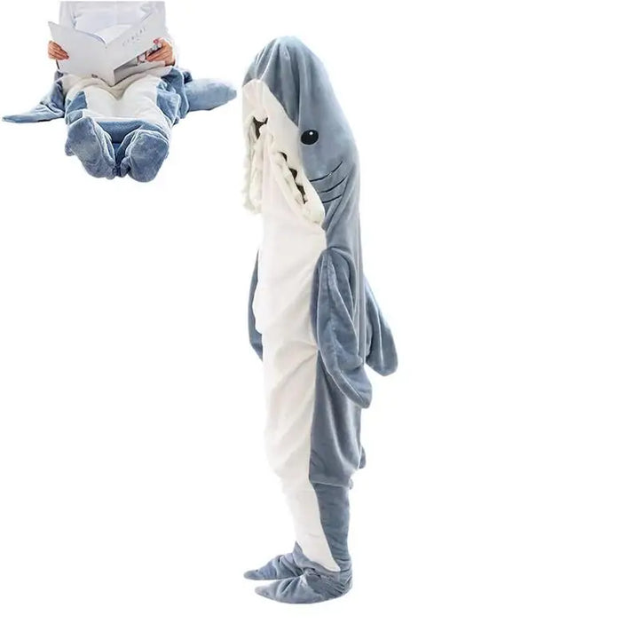 A person wearing soft, full-body shark pajamas that cover them from head to toe. Inset shows someone sitting with legs inside the cozy pajamas, appearing as if theyre in a shark’s mouth while reading a book.