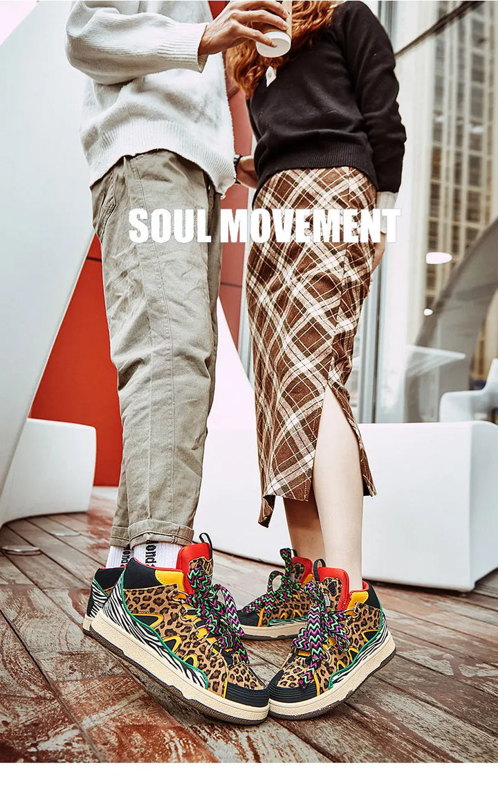 Two people face each other indoors; one in khaki pants, the other in a plaid skirt with a slit. Both wear lightweight animal print shoes. The words SOUL MOVEMENT appear in large white text over the image.