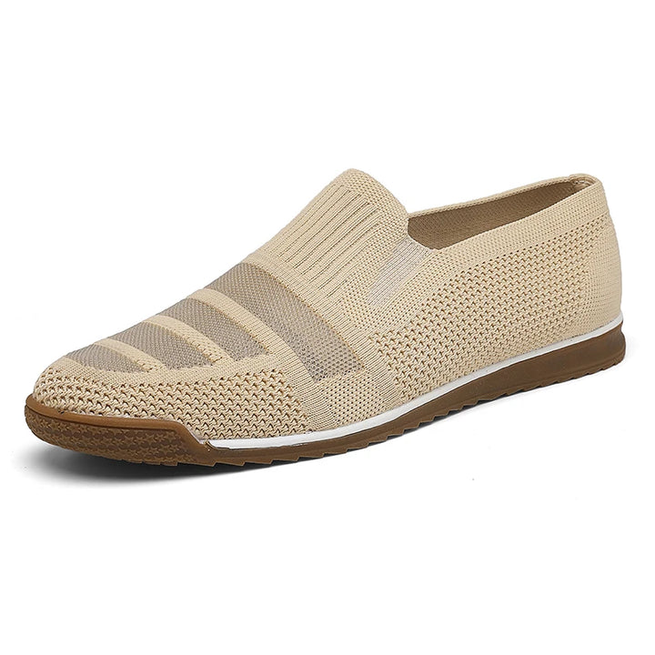 Beige slip-on men's casual loafers with a knitted upper, textured pattern, and a brown sole. These breathable shoes feature a low-cut design, elastic sections for easy wear, and a comfortable canvas lining.