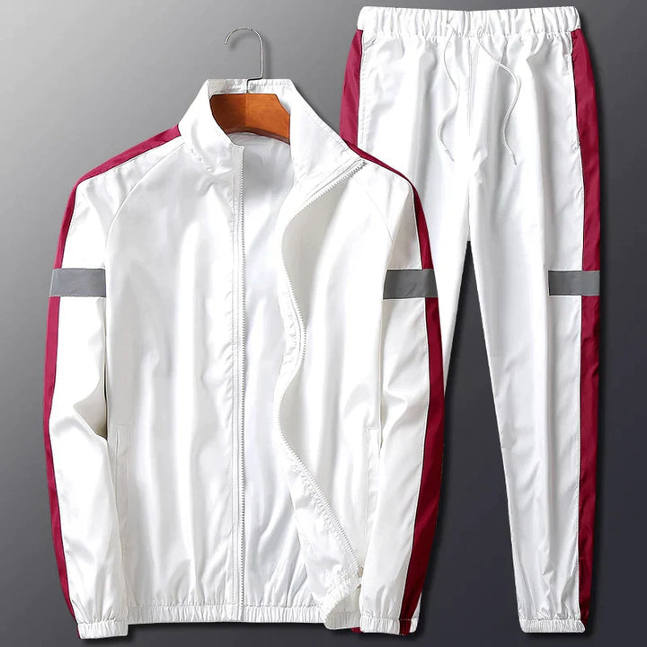 A white two-piece activewear set with maroon side stripes and gray reflective bands on the sleeves and pant legs, displayed on a hanger against a gray background. The jacket is unzipped and features a stand-up collar.