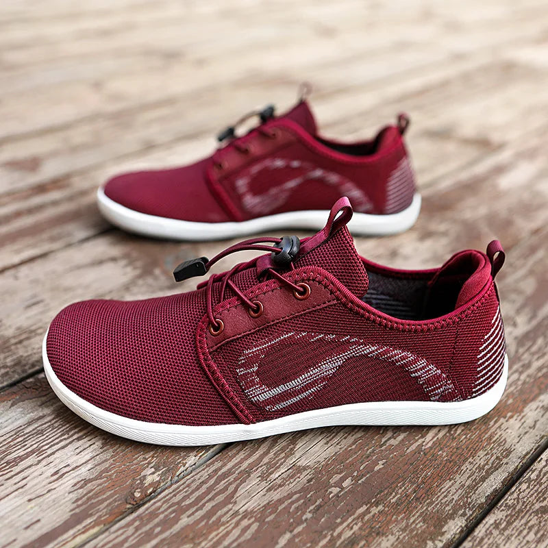 A pair of maroon athletic shoes with cushioned soles, white accents, and black lace locks, displayed on a weathered wooden surface.