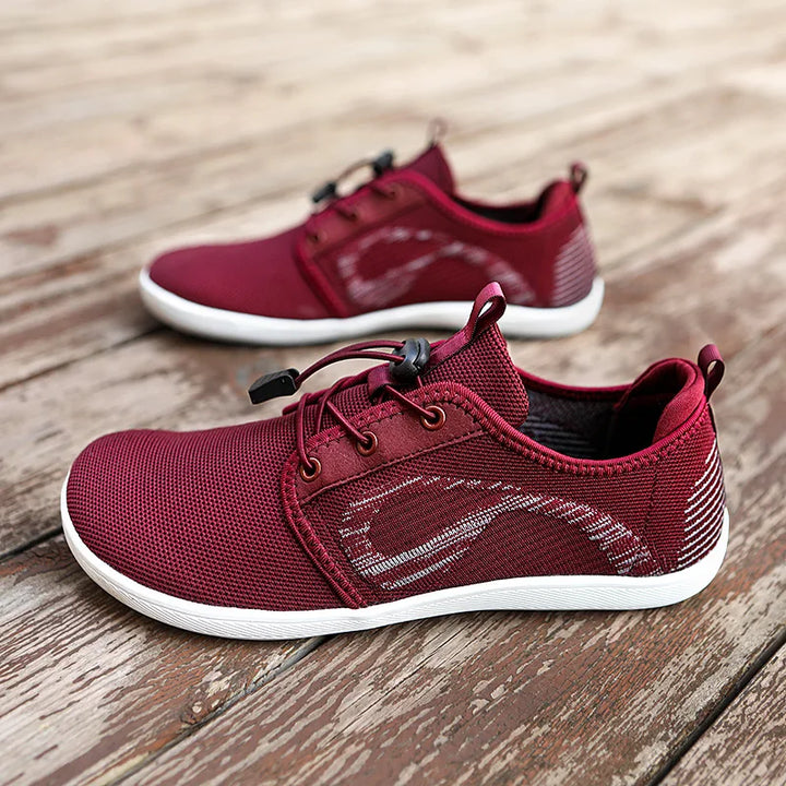 A pair of maroon athletic shoes with cushioned soles, white accents, and black lace locks, displayed on a weathered wooden surface.