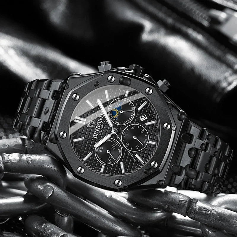 A black luxury stainless steel watch with a metal band and multiple chronograph dials is displayed on a background of metallic chains and dark leather. The watch face features silver accents, prominent screw details, and precision quartz movement.