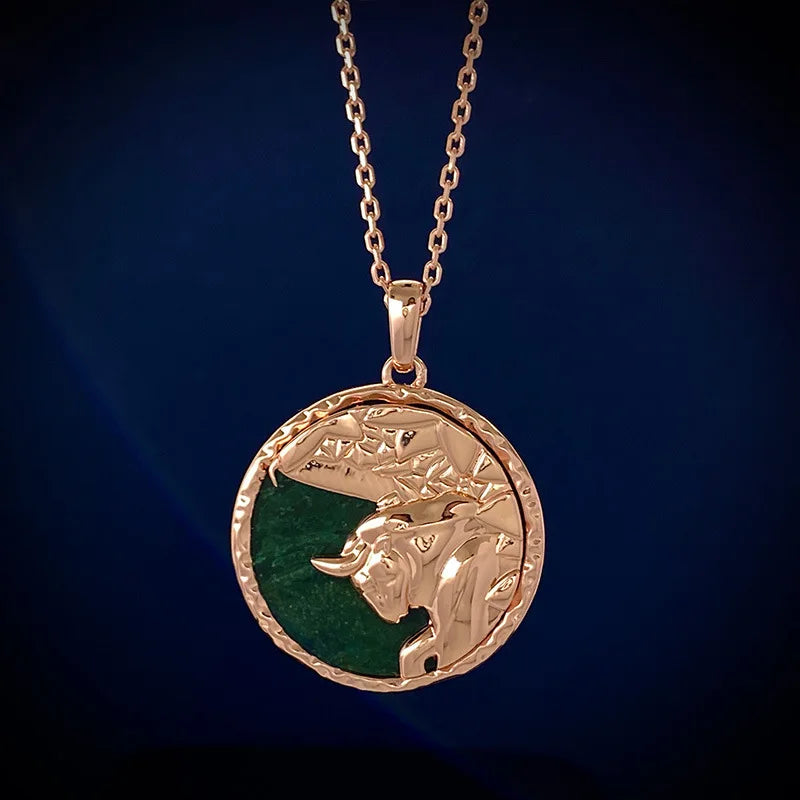 A gold zodiac necklace with a round pendant featuring an embossed bulls head on a green background, displayed against a dark blue backdrop—a striking piece of astrology jewelry.
