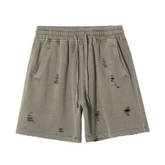 Light olive green vintage baggy shorts with an elastic waistband, drawstring, side pockets, and a cut-up design featuring distressed, ripped details on the front.