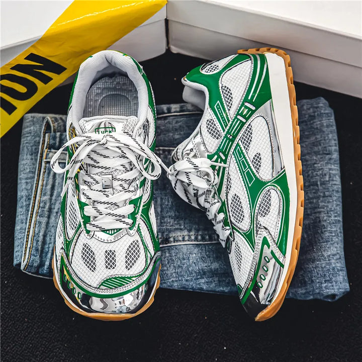 A pair of white sneakers with green and silver accents, cushioned insoles, and gum soles sit on folded blue jeans next to a yellow caution sign on a black surface.