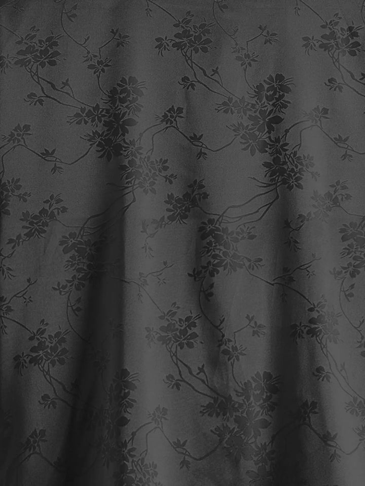 Dark, subtly glossy breathable fabric with a floral and vine pattern. The soft folds and drapes make it ideal for men's summer shirts, with plant motifs creating an elegant, understated texture against the black background.