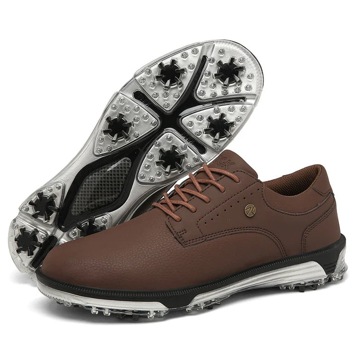 A pair of brown genuine leather golf shoes with textured uppers and spiked rubber soles, designed for advanced grip technology on the course. One shoe is upright and the other is shown sole-up.