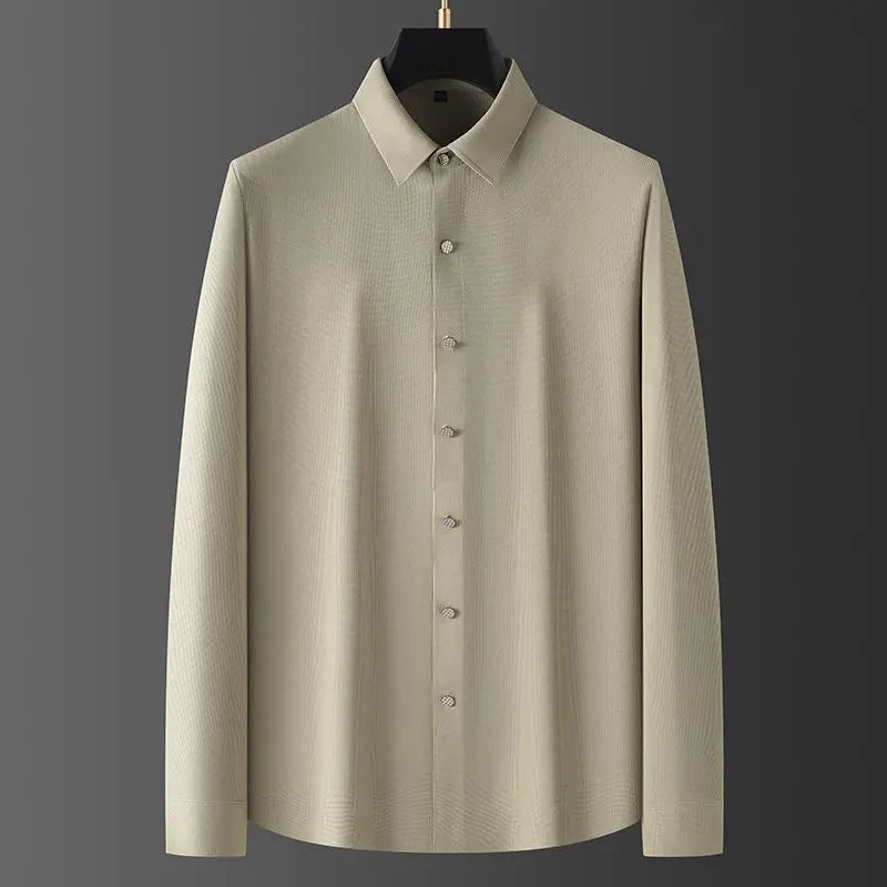 A long-sleeve, light beige wrinkle-resistant shirt with a pointed collar, displayed on a hanger against a dark gray background.