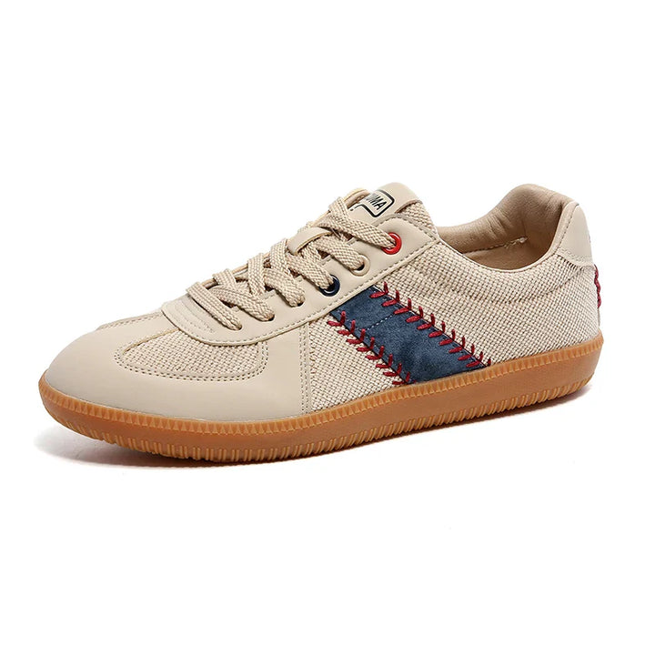 A beige sneaker with a gum sole, blue and red zigzag stitching on the side, mesh and leather-like panels, and beige laces. These lightweight breathable sneakers feature EVA midsole cushioning. Photographed on a white background.