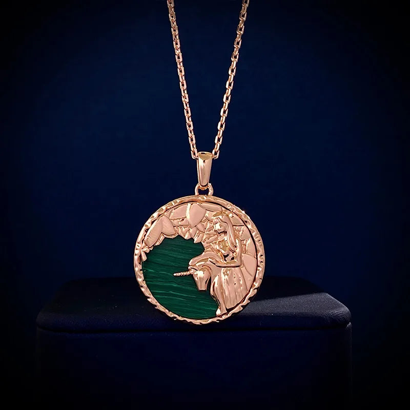 A gold zodiac necklace featuring an engraved lion’s head and mane over a green background, displayed against a dark blue setting—a striking piece of astrology jewelry.