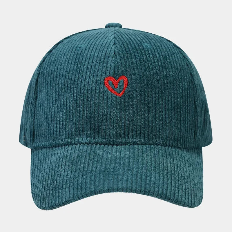 A teal corduroy baseball cap featuring a small red heart embroidery on the front and a comfortable FlexFit band, photographed against a plain white background.