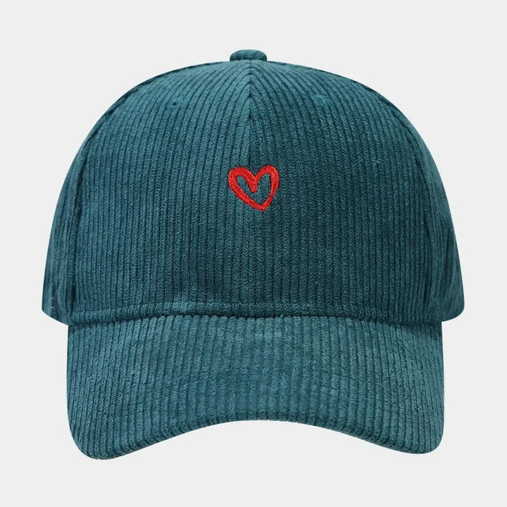 A teal corduroy baseball cap featuring a small red heart embroidery on the front and a comfortable FlexFit band, photographed against a plain white background.