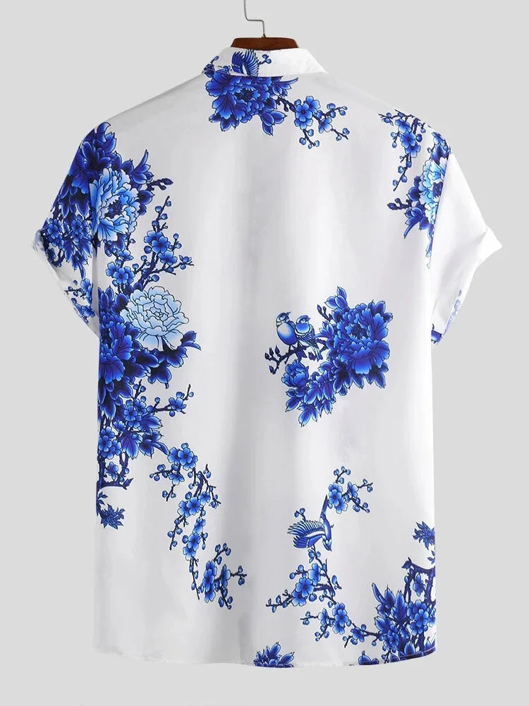 A summer-ready, white short-sleeve floral design shirt with blue bird print on the back, crafted from a cotton-silk blend and displayed on a hanger against a light gray background.