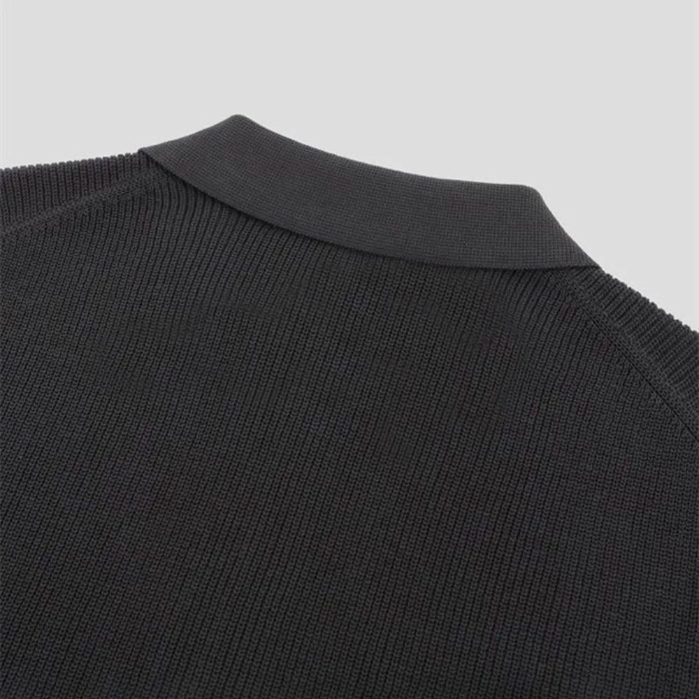 Close-up of the upper back and collar of a black knitted sweater, showing the texture of the fabric and ribbed detailing on the crew neckline against a plain light background.