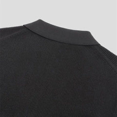 Close-up of the upper back and collar of a black knitted sweater, showing the texture of the fabric and ribbed detailing on the crew neckline against a plain light background.