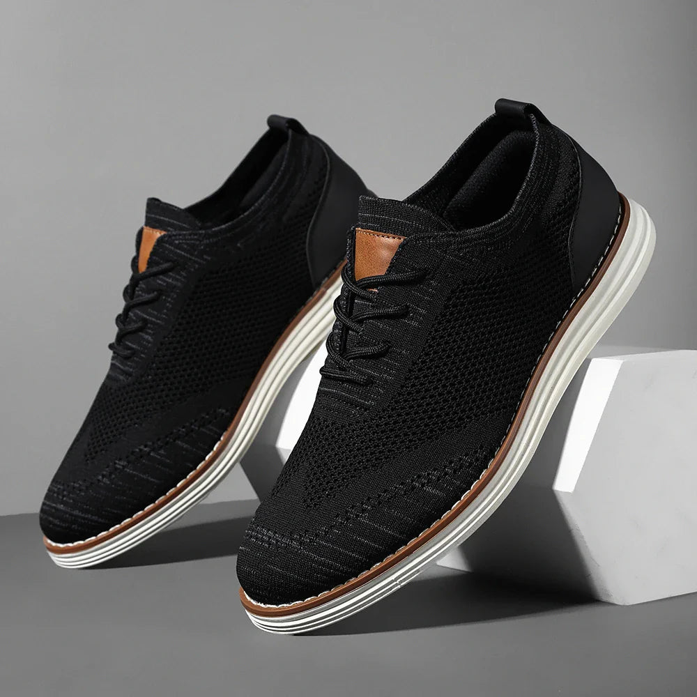 A pair of stylish black breathable knit sneakers with white soles and brown accents, displayed against a gray background with one shoe propped up on a white block.
