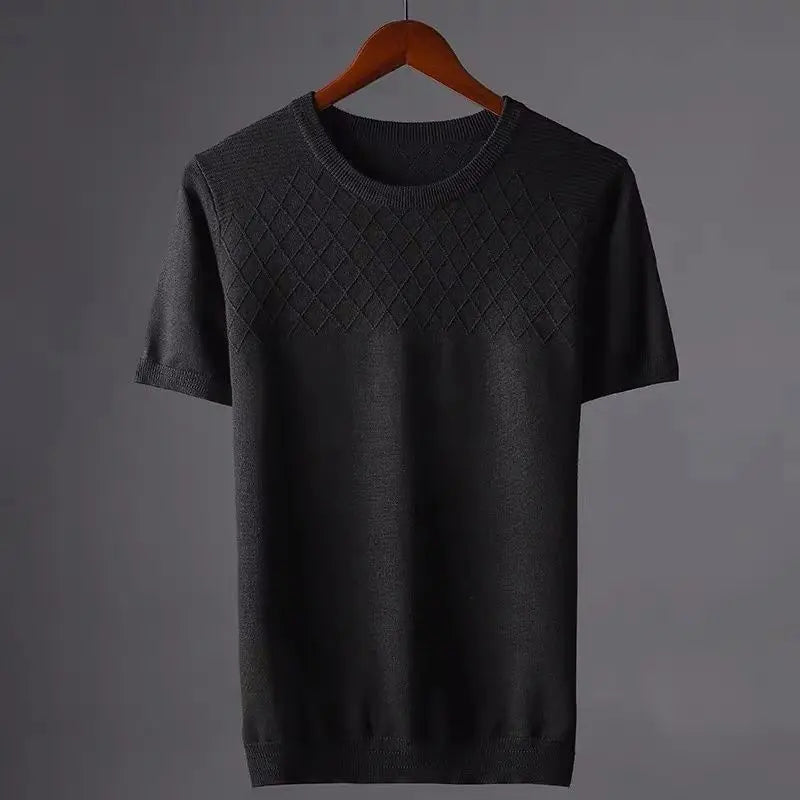 A short-sleeved, dark gray knit sweater with a classic fit hangs on a wooden hanger. The upper chest area features a diamond-pattern texture, while the rest is plain. The background is a simple, neutral gray.