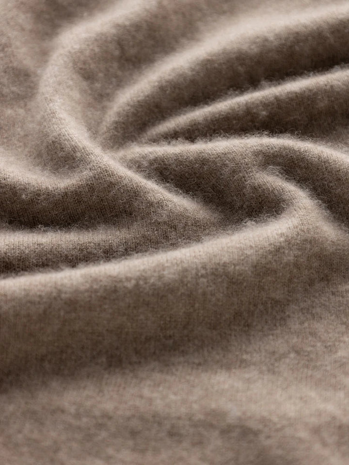 Close-up of soft, light brown fabric with a fuzzy texture and gentle folds, highlighting the smooth and cozy appearance of the Matilda Wrap Dress with its elegant V-neck wrap design.