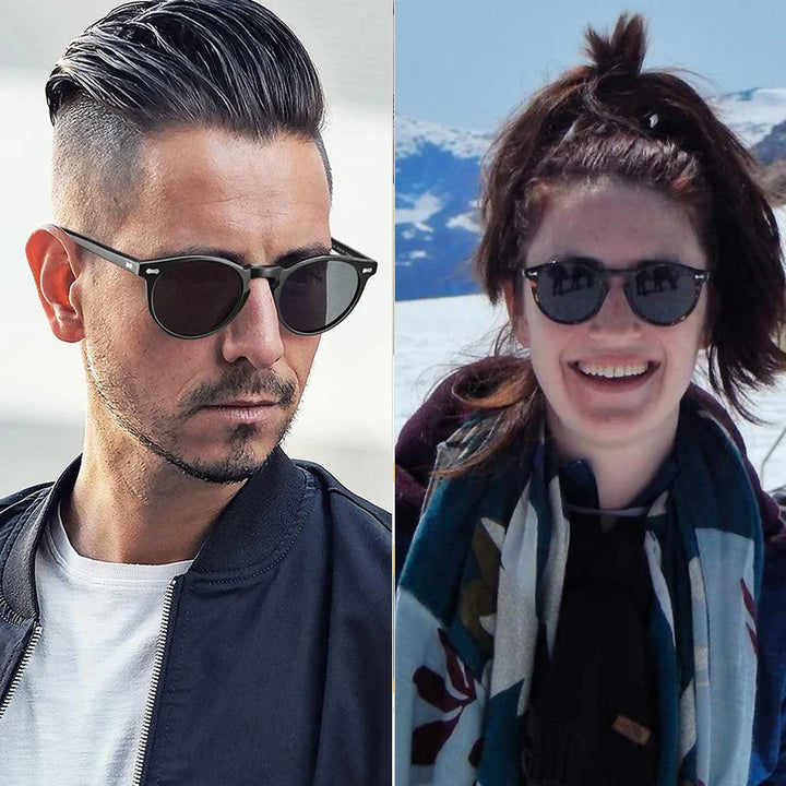 A man with slicked-back hair and a woman in a ponytail both wear trendsetting sunglasses; the man is dressed in a jacket, and the smiling woman enjoys the outdoors with mountains and snow in the background.