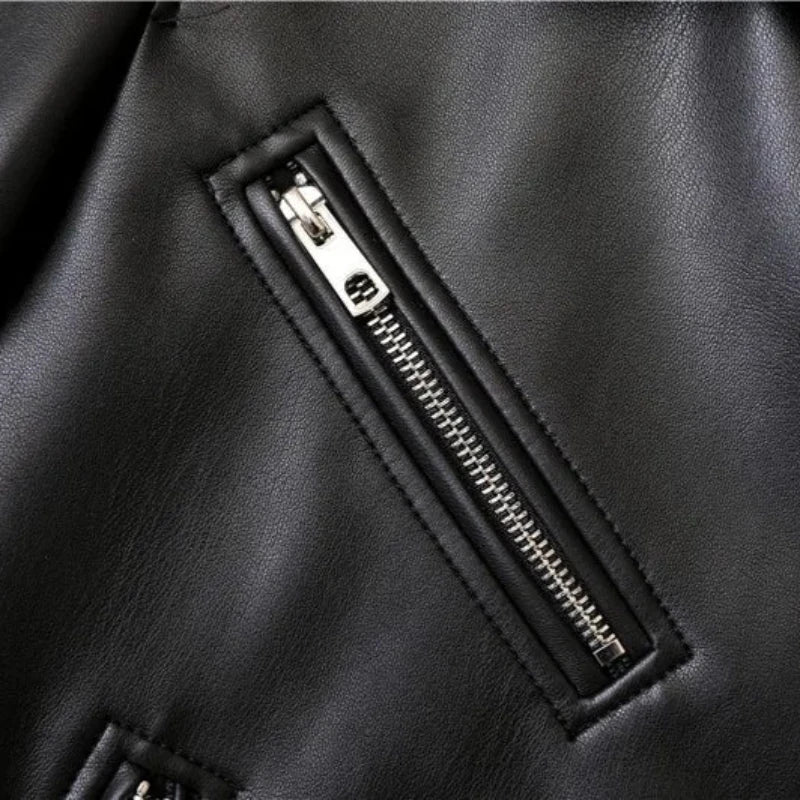 Close-up of a black leather jacket featuring a shiny silver zipper, sewn diagonally with visible stitching around the zipper area, highlighting the texture and details of the material.