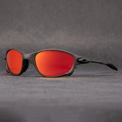 Matte black outdoor eyewear with curved frames and bright orange mirrored lenses, offering UV protection, displayed against a plain gray background.