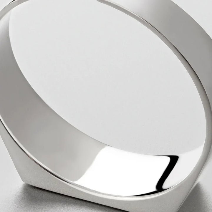A close-up view of a modern, minimalist silver bracelet crafted from scratch-resistant stainless steel with smooth, reflective surfaces, photographed against a light gray background.