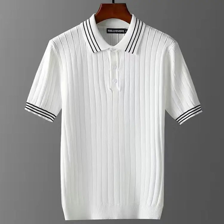 A premium polo shirt featuring a white short-sleeve knit design with vertical ribbed texture, black double stripes on the collar and cuffs, and subtle corduroy detailing, displayed on a wooden hanger against a gray background.
