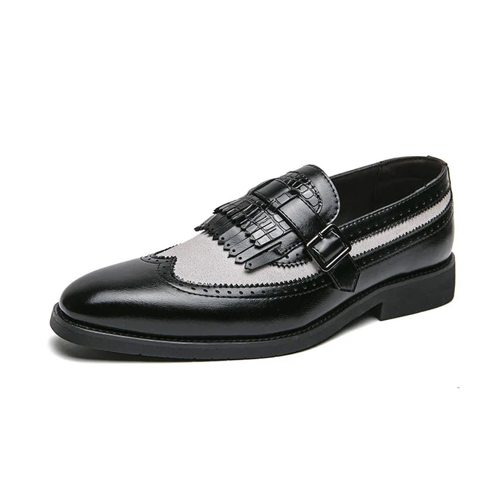 A stylish black and gray premium leather shoe with a slip-on design, decorative fringe, buckle strap, and classic wingtip detailing, displayed on a white background.