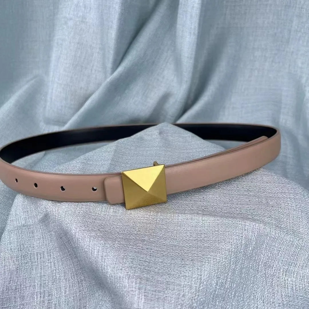 A beige leather belt with an adjustable length and a large, square gold buckle displayed on a light gray textured fabric background.