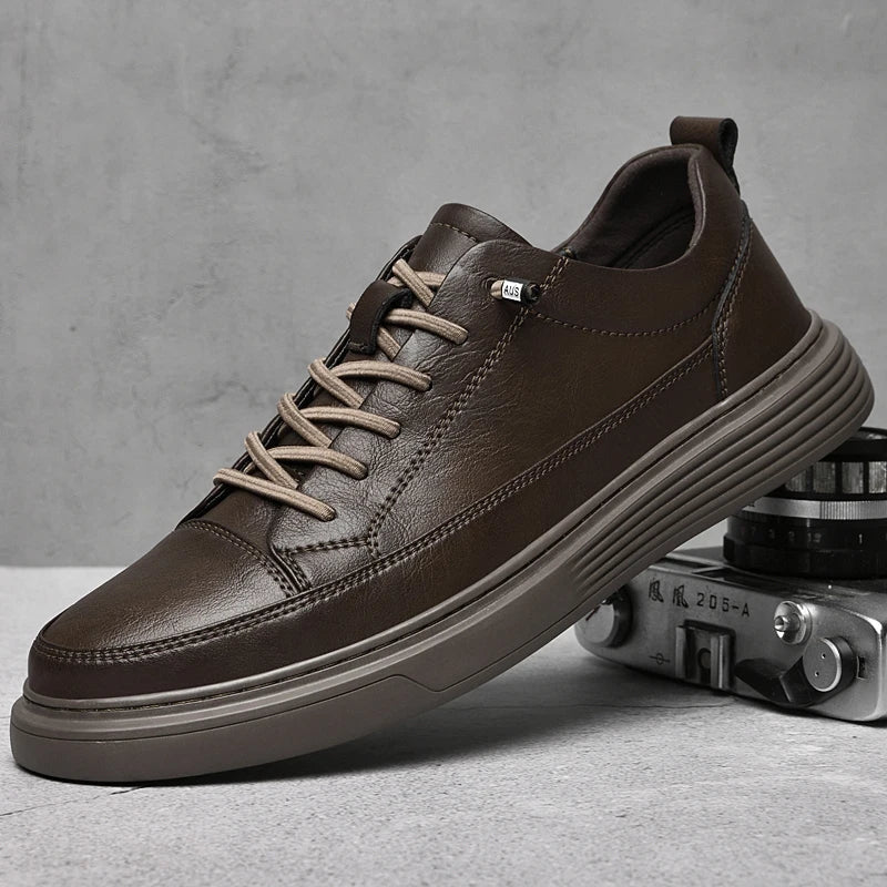 A brown genuine leather sneaker with beige laces is displayed on top of a vintage camera against a gray background. The shoe features a thick, textured sole, minimalistic stitching, and comfort-boosting RunForm insoles.