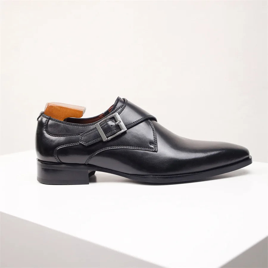 A handcrafted black leather monk strap shoe with a silver buckle, made from premium Italian leather, displayed on a white platform against a plain light background.